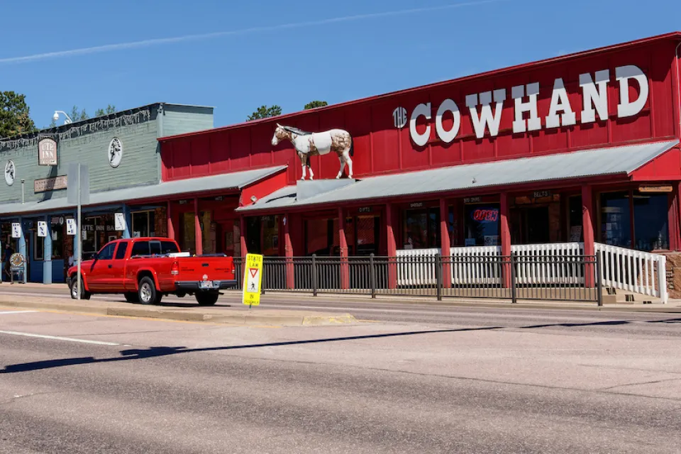 Single-story western-style buildings in Woodland Park, Colorado. Red building on corner labeled "COWHAND" in white text.